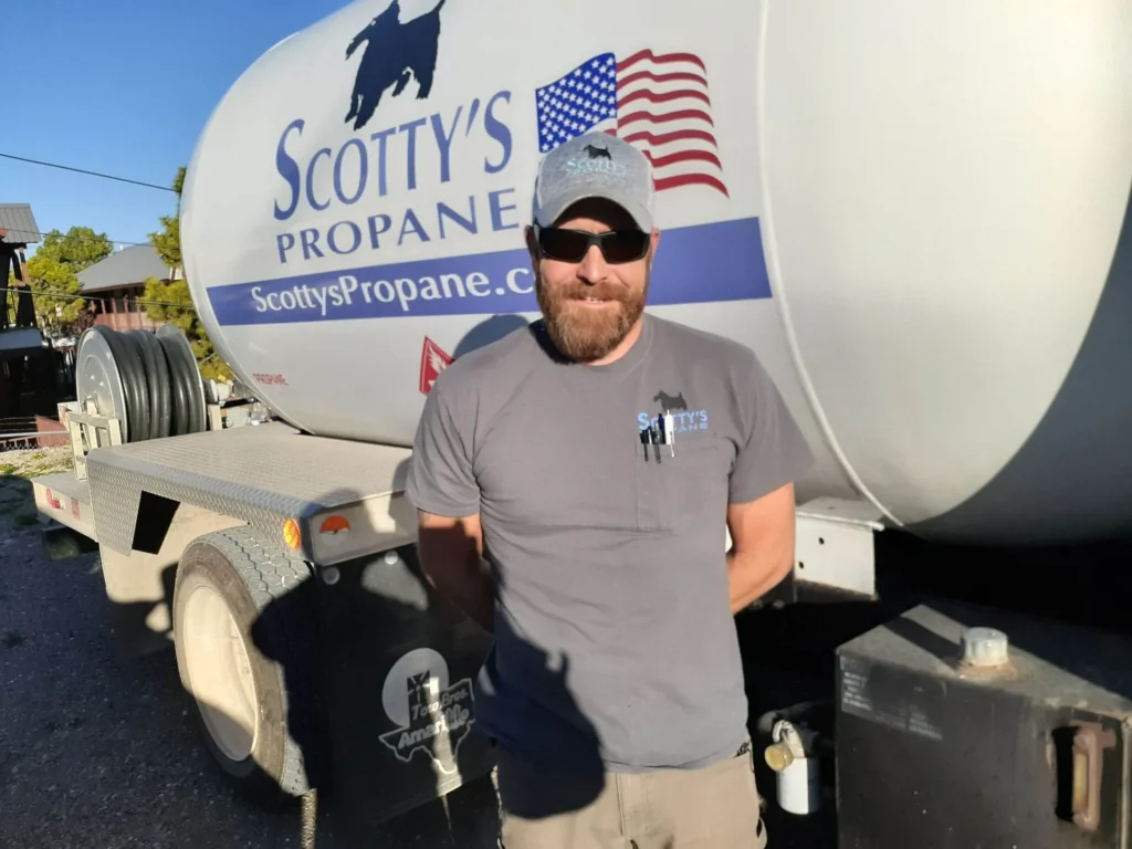 gentleman employee with sunglasses and a hat standing in front of scotty's propane delivery truck