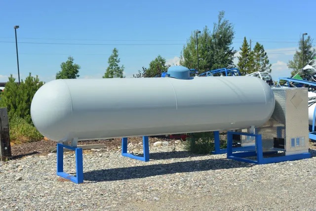 Large horizontal propane storage tank on blue support stands outdoors